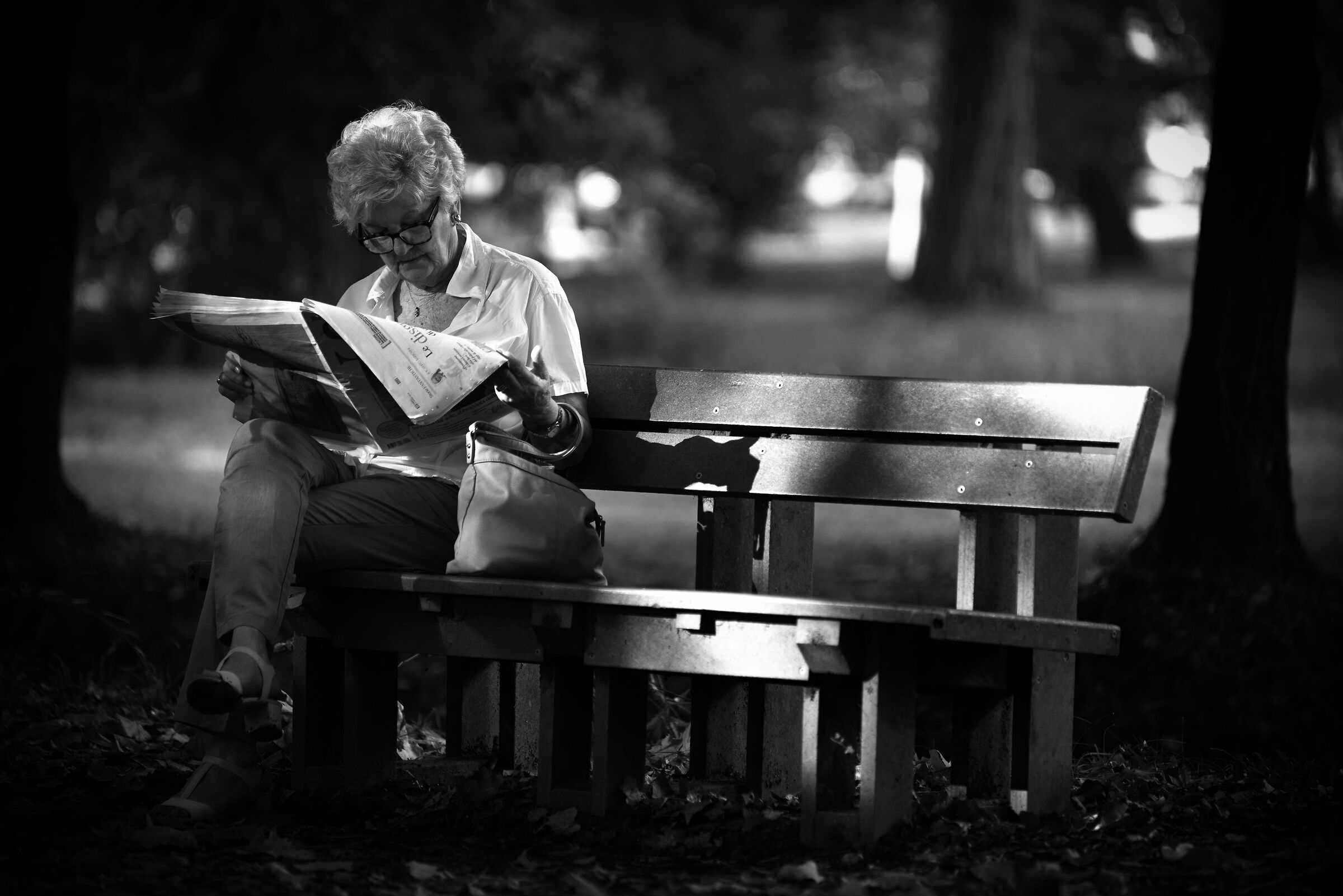 A grandni who reads the newspaper on the bench...